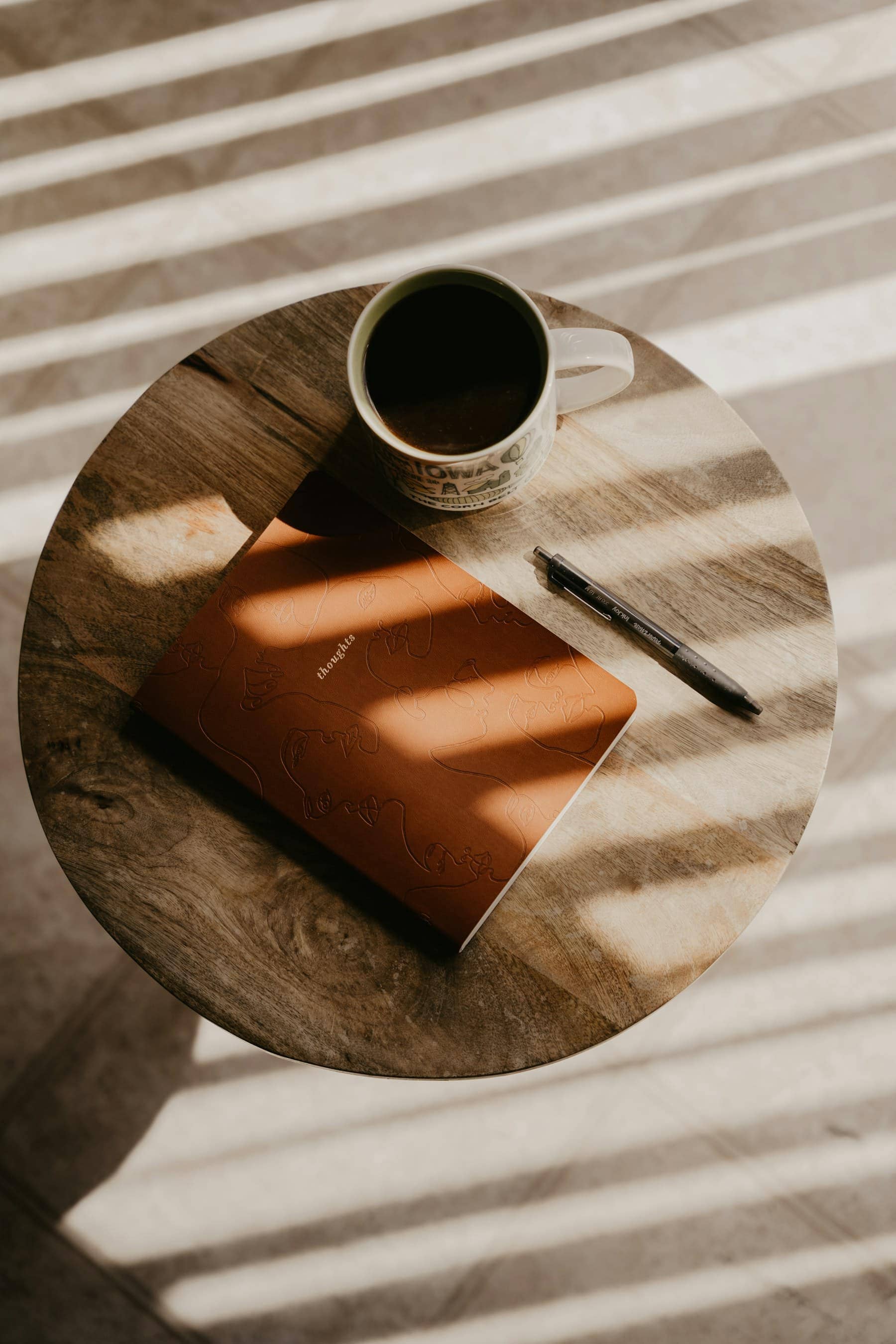 Une tasse de café et un carnet ouvert sur une table en bois