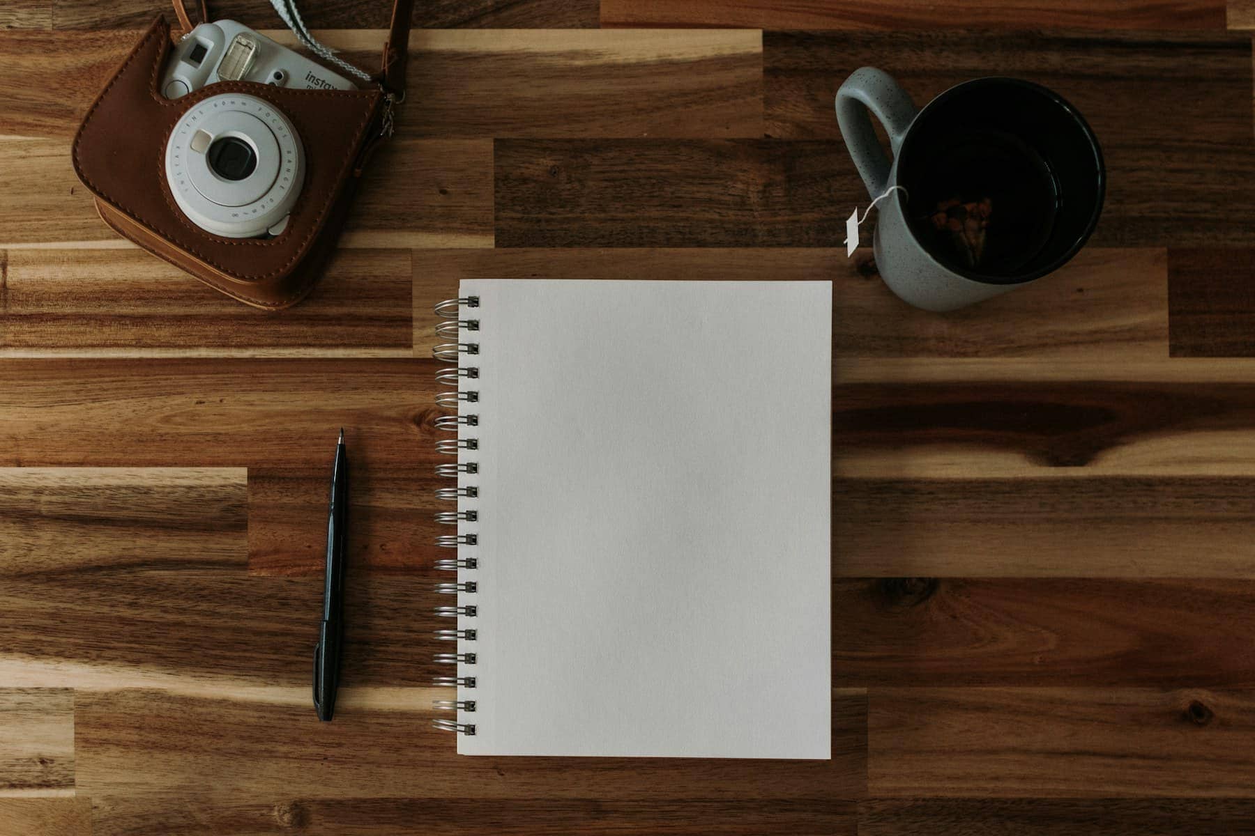 Un carnet, un stylo et une tasse de café posés sur une table en bois